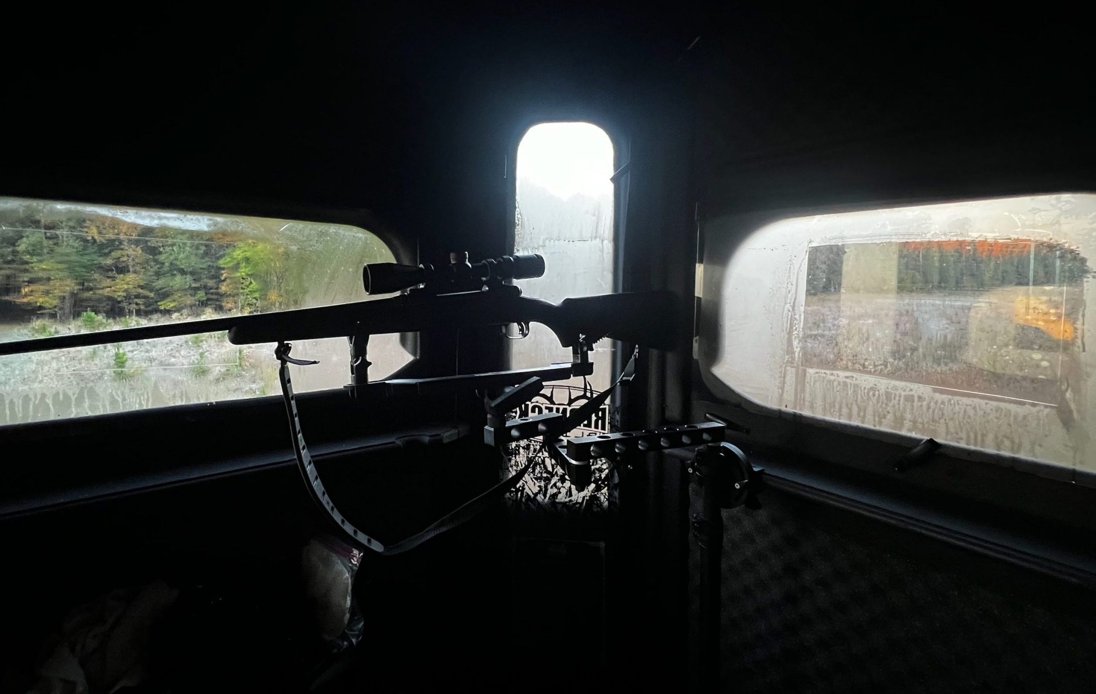 view from inside a deer blind with a rifle Hunter-Vision is applied to all the windows of the blind clearly showing the effectiveness of Hunter-Vision Preventing Fog on the windows.